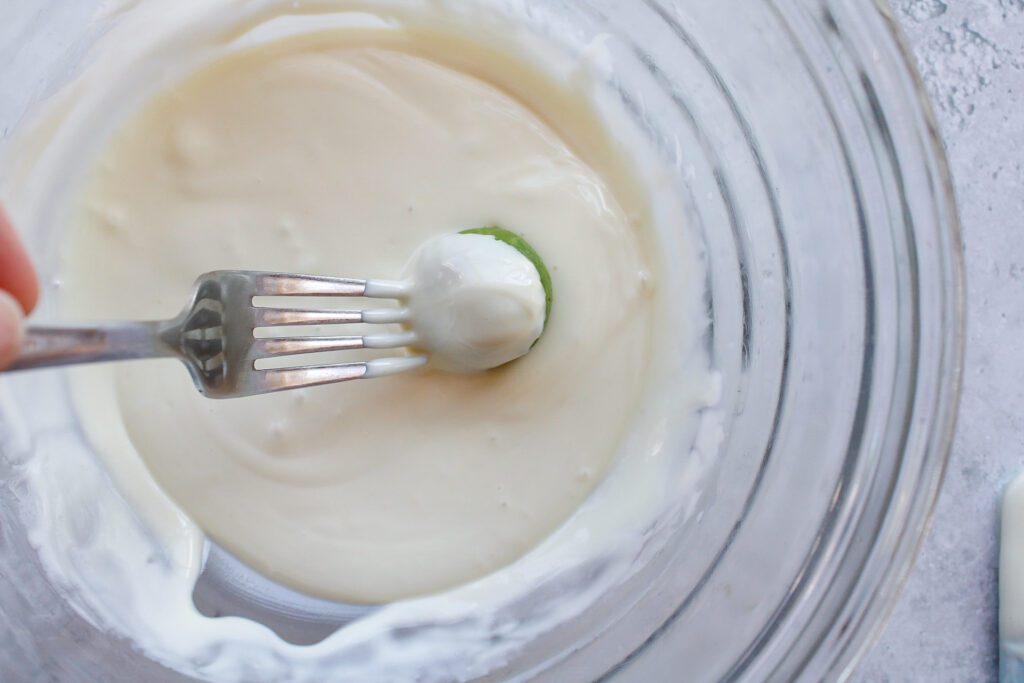 a fork rolling a matcha truffle through melted white chocolate