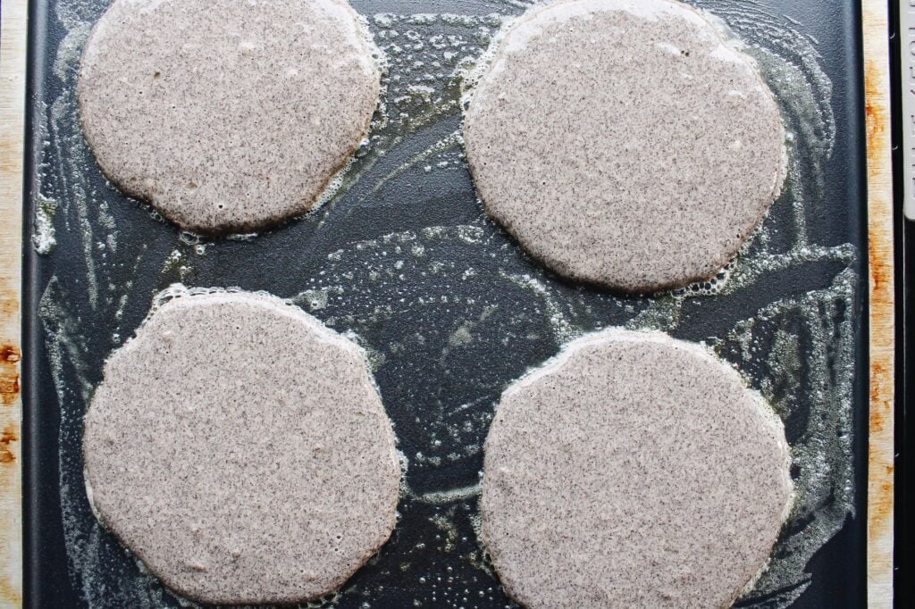 four buckwheat banana pancakes on a griddle