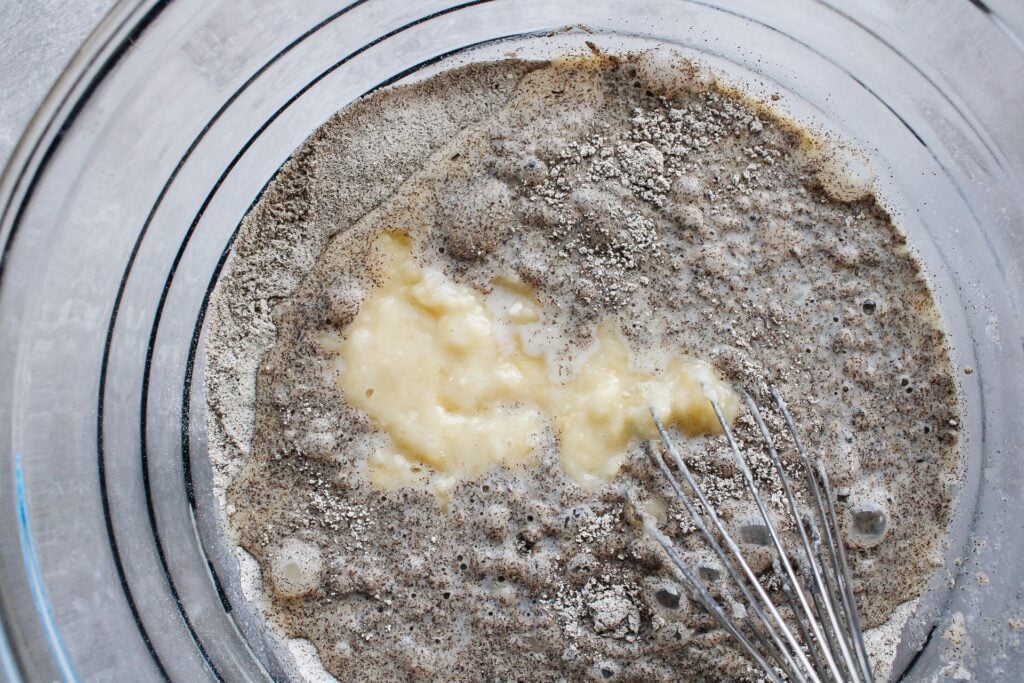 wet and dry ingredients for buckwheat banana pancakes being whisked in a mixing bowl