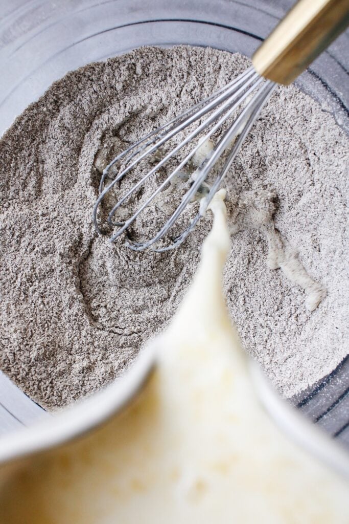 wet ingredients being poured into a bowl with dry ingredients for buckwheat pancakes