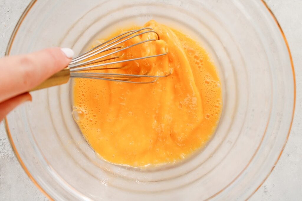 eggs being whisked in a clear bowl