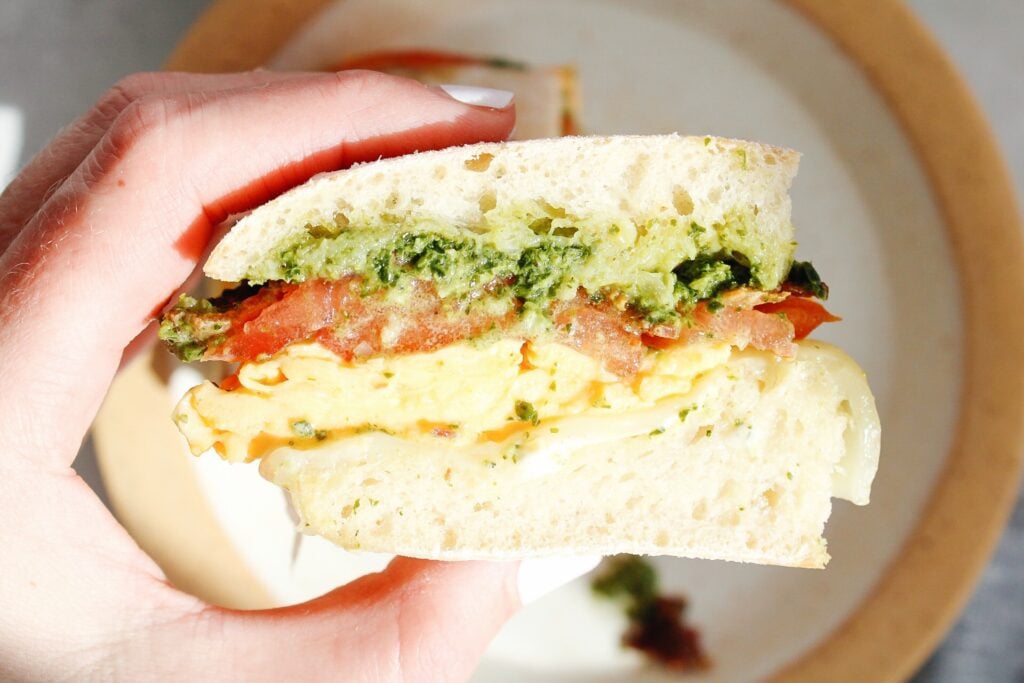 close up of pesto egg sandwich held in beckys hand