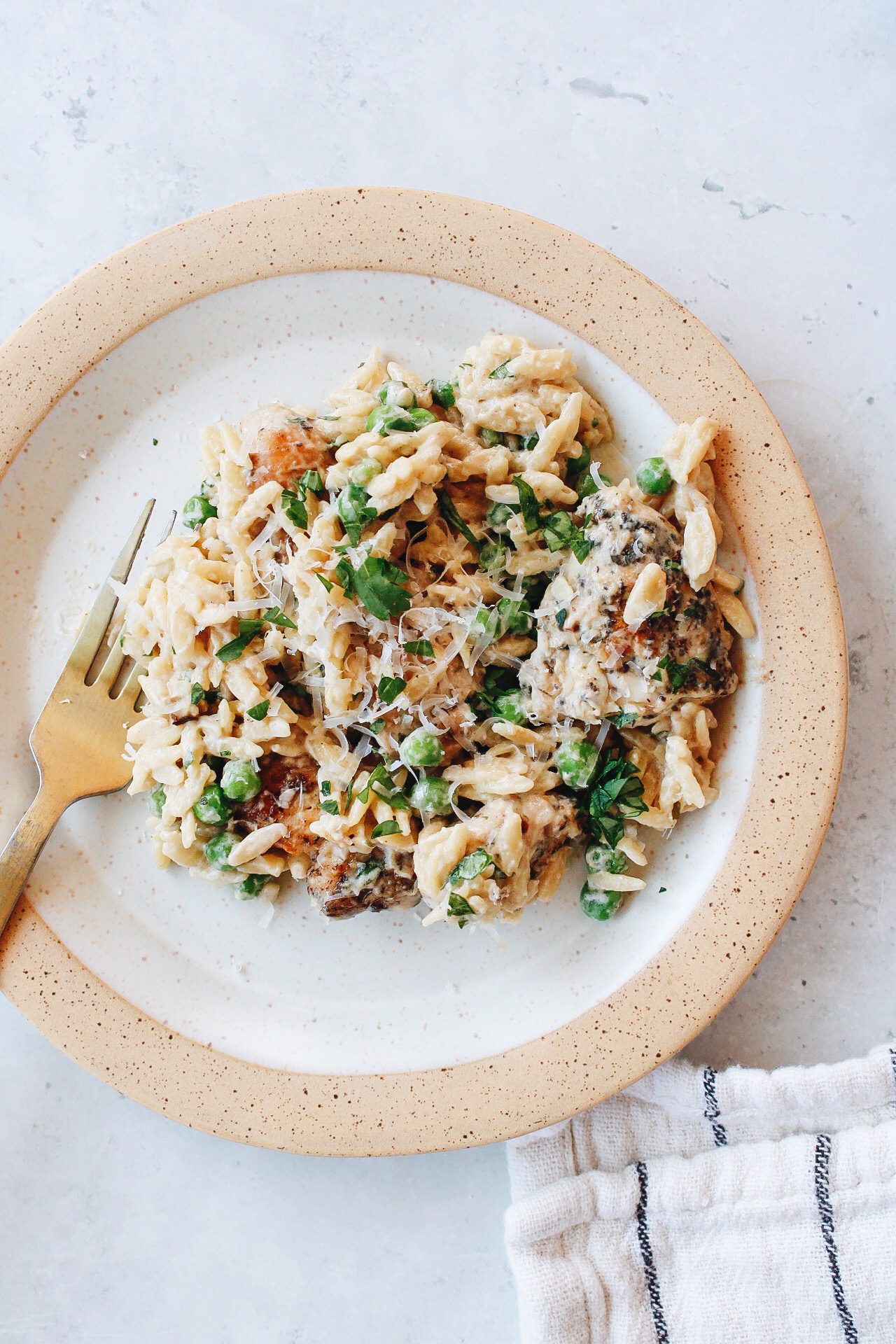 boursin chicken orzo on a beige plate with a striped napkin