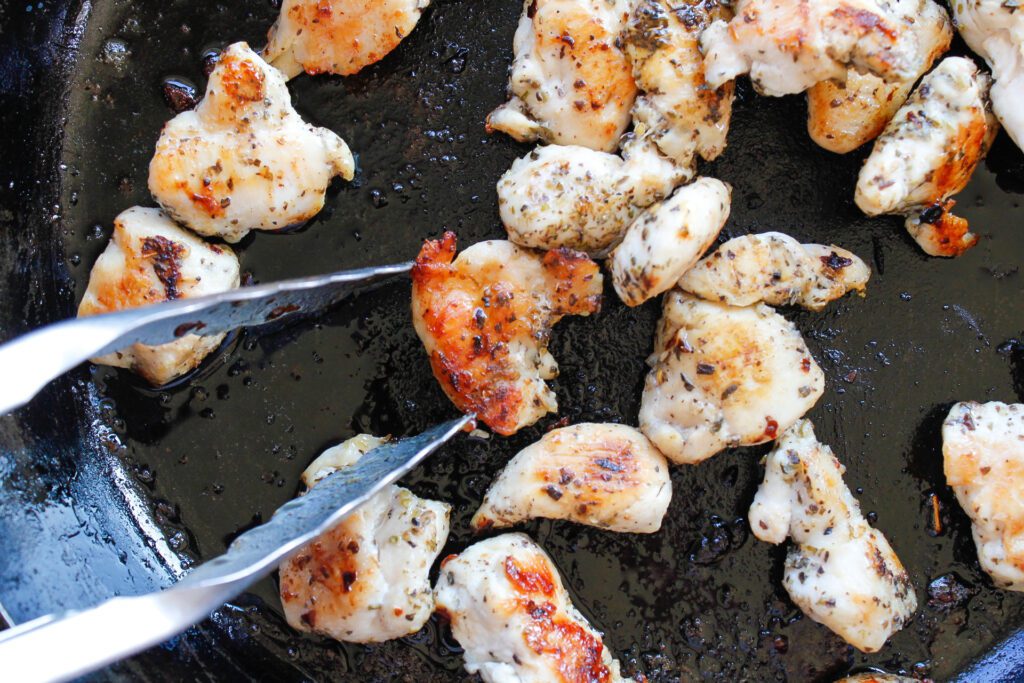 chicken chunks cooking in cast iron pan