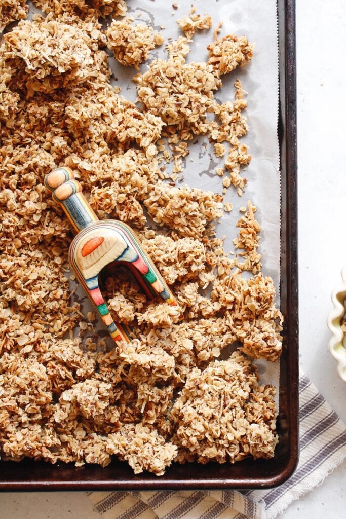 cardamom granola on a baking sheet with crunchy clusters