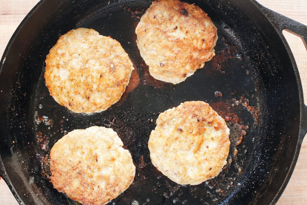 ground chicken burger patties cooked in a skillet