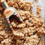 cardamom granola on a baking sheet with a rainbow colored scoop