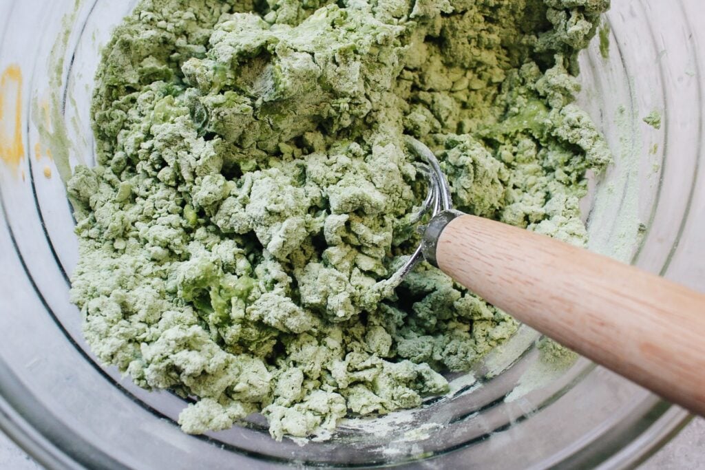 matcha scone dough being mixed with a dough whisk