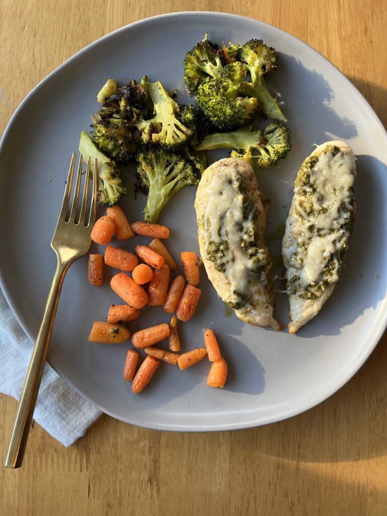 pesto chicken on a plate with roasted carrots and broccoli