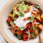 easy potato taco bowl topped with guacamole and sour cream