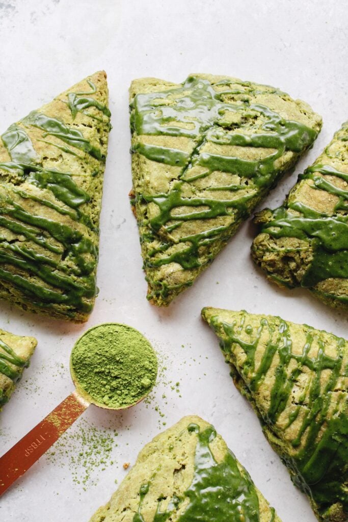 matcha scones on a gray background with a spoonful of matcha next to it