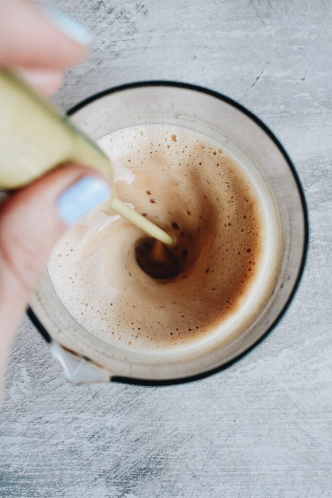 sweetened condensed milk being frothed into black tea