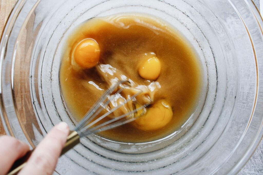 eggs being beaten with melted butter, sugar and vanilla