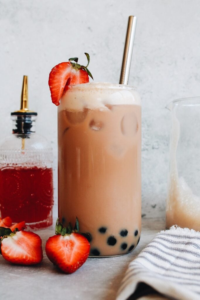 strawberry bubble tea in a clear glass with a boba straw